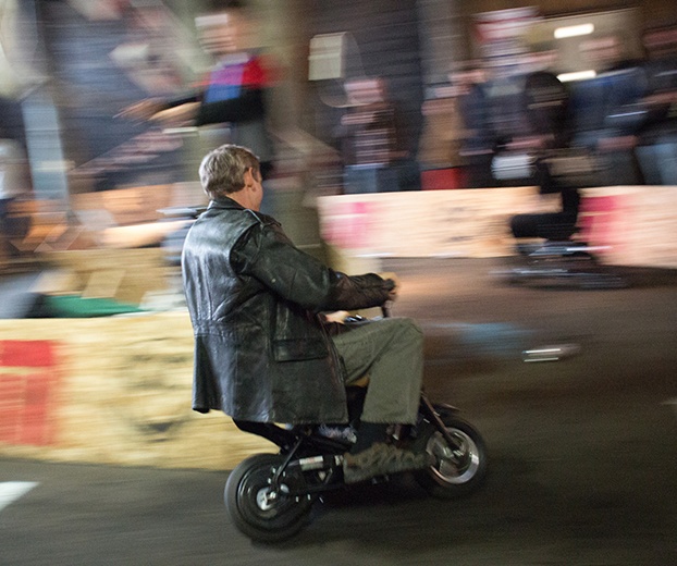 An adult wearing a leather jacket rides a mini bike
