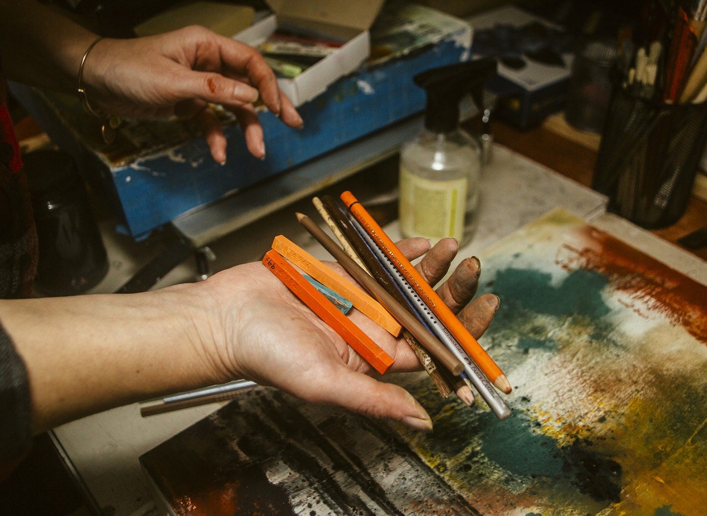 an artist holding pencils, crayons and other art-making implements