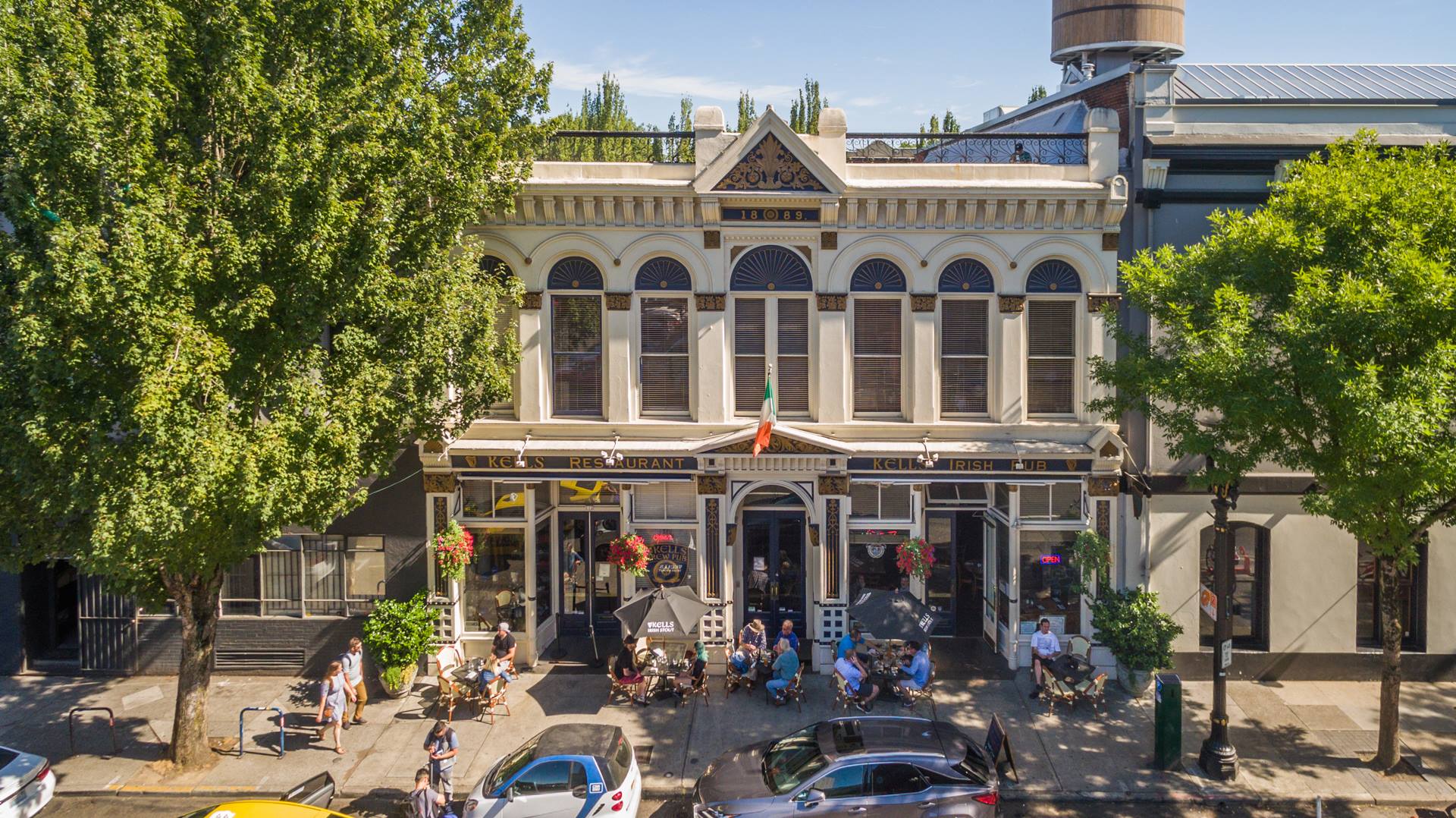 the facade of a large Irish pub with groups of people eating and drinking out front