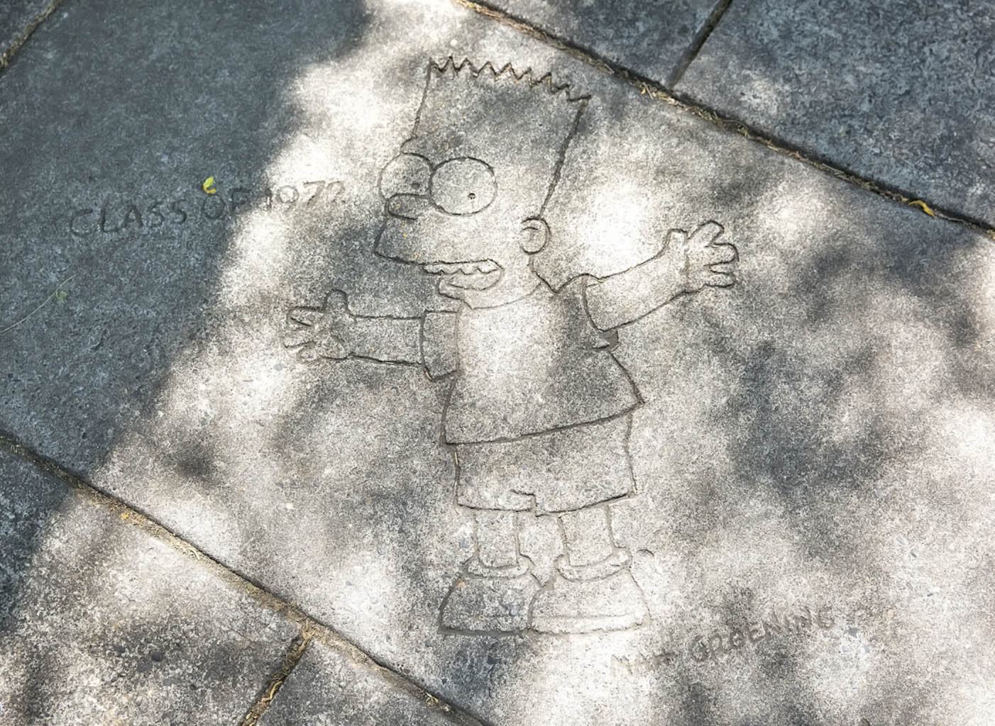 a depiction of cartoon character Bart Simpson on a sidewalk