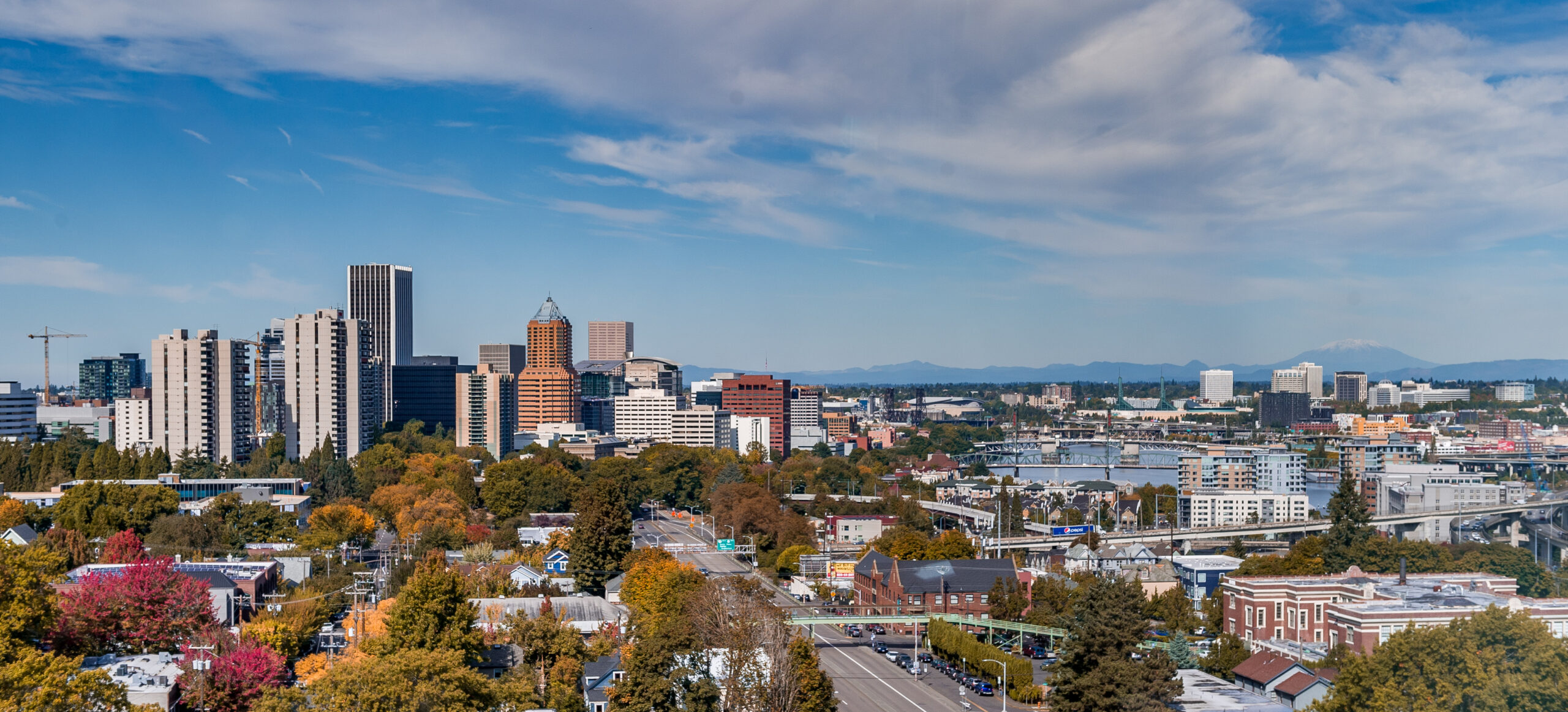 city view on early fall day, tree leaves are changes colors, and there is a light blue sky with passing clouds