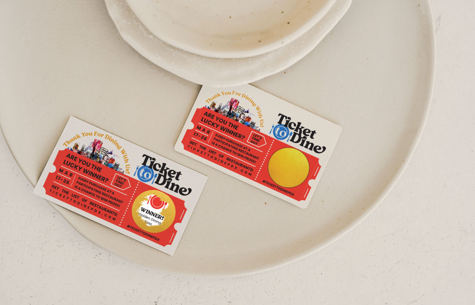 two colorful scratch-off tickets that read Ticket to Dine and Thank You For Dining With Us rest on a large white plate on a white countertop