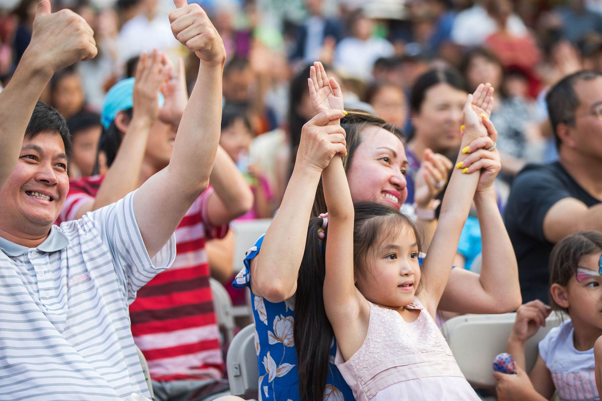 a family sitting in chairs raise their arms while watching a performance