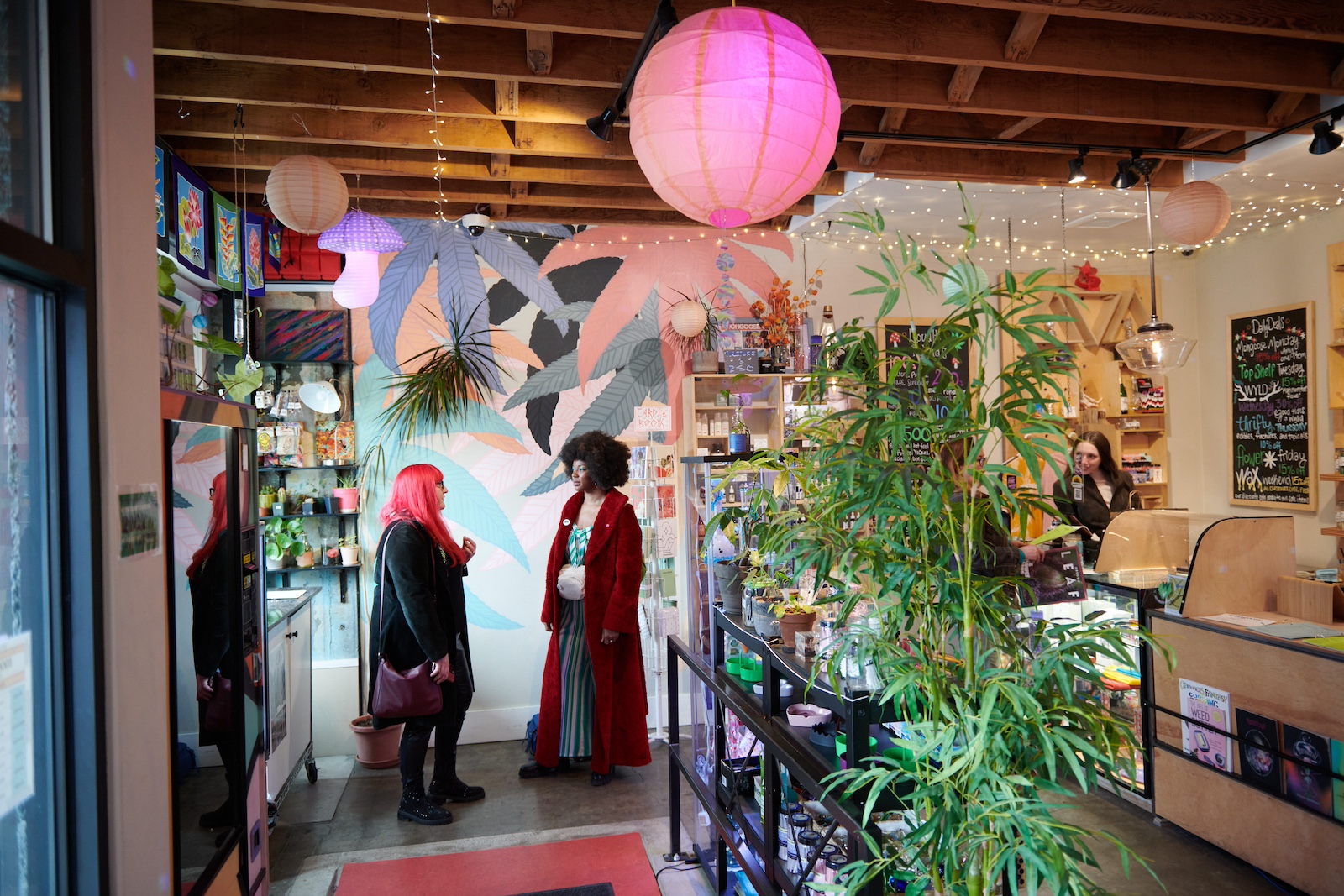 two people talking in the lobby of a cannabis shop with another person behind the counter