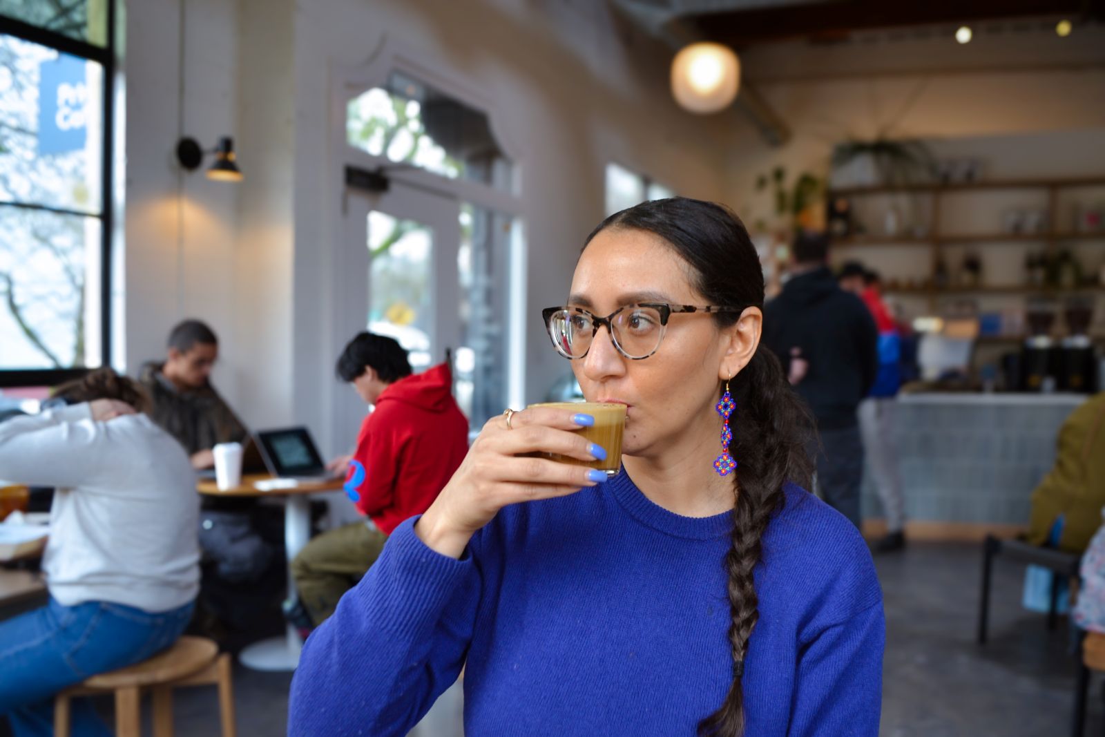 a person sips an espresso drink in a bright airy café