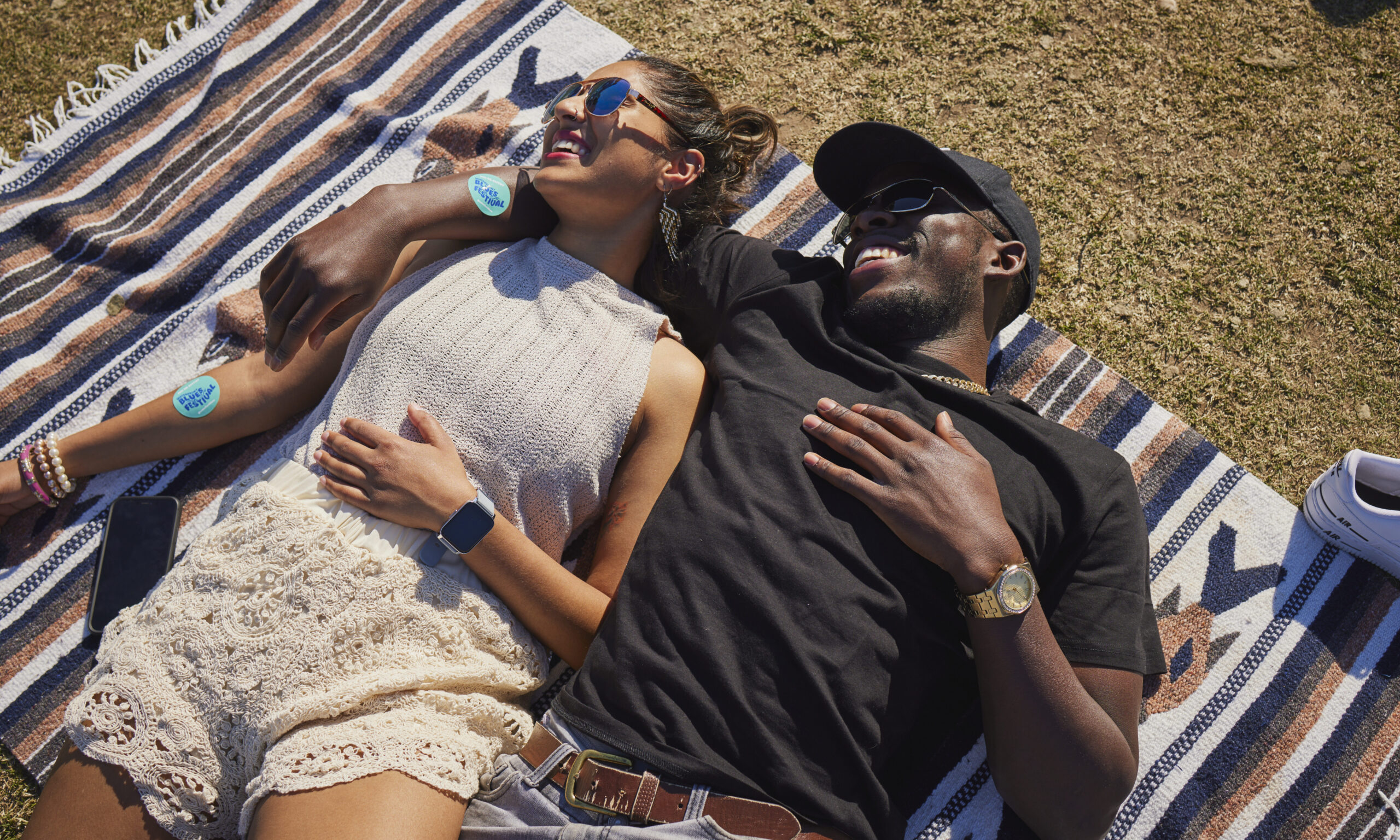 two people lying down in the sunshine on a blanket
