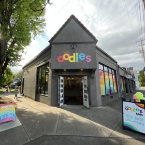the entrance to a toy store with a sign above it that says “Oodles” in colorful letters