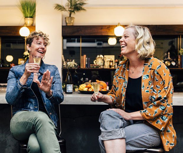 Two women sitting and laughing while having a drink