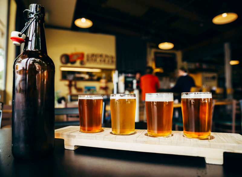 a tasting flight of beers next to an open bottle