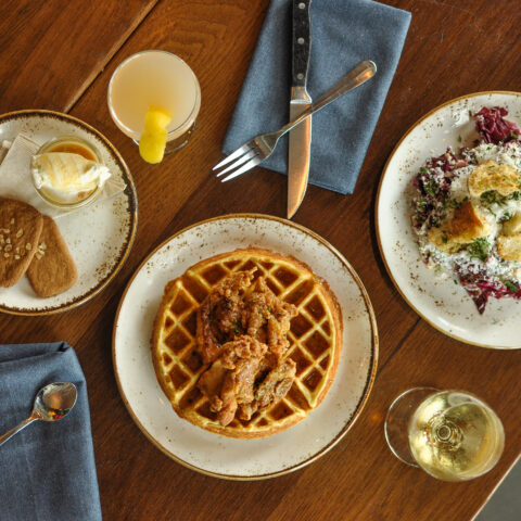 a spread of appetizing dishes alongside glasses and flatware on a wooden table